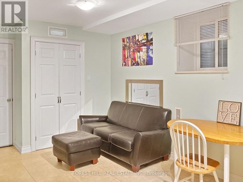 A living room with a brown leather couch and a white chair.