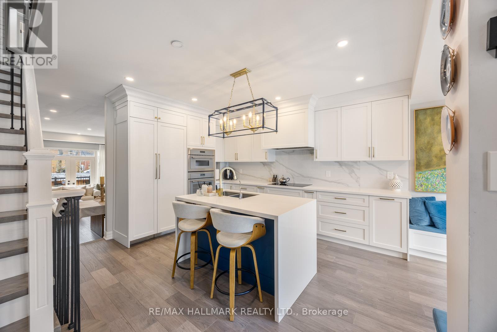 A modern kitchen with white cabinets and a wooden floor.