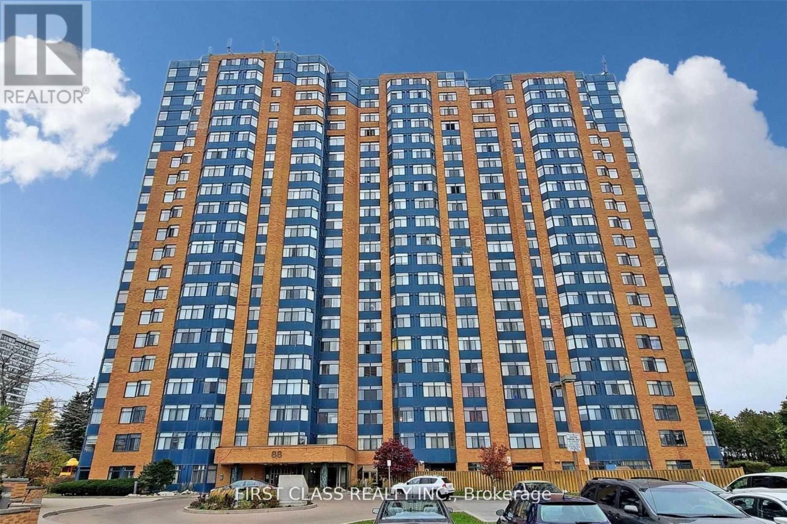 A tall building with many windows is under a blue sky.