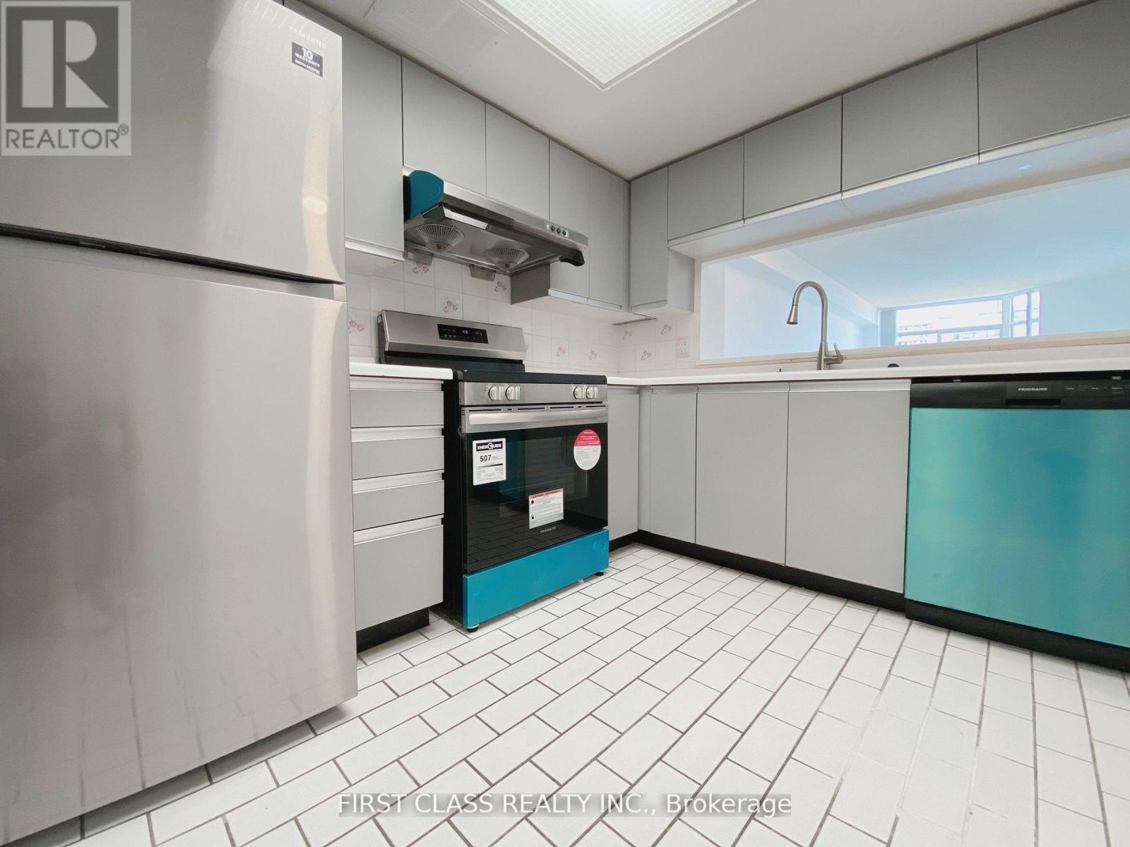 A kitchen with a white tile floor and a stainless steel refrigerator.