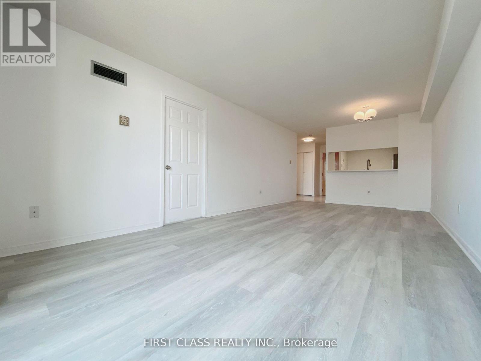 A spacious room with a white door and a small shelf with a light on.