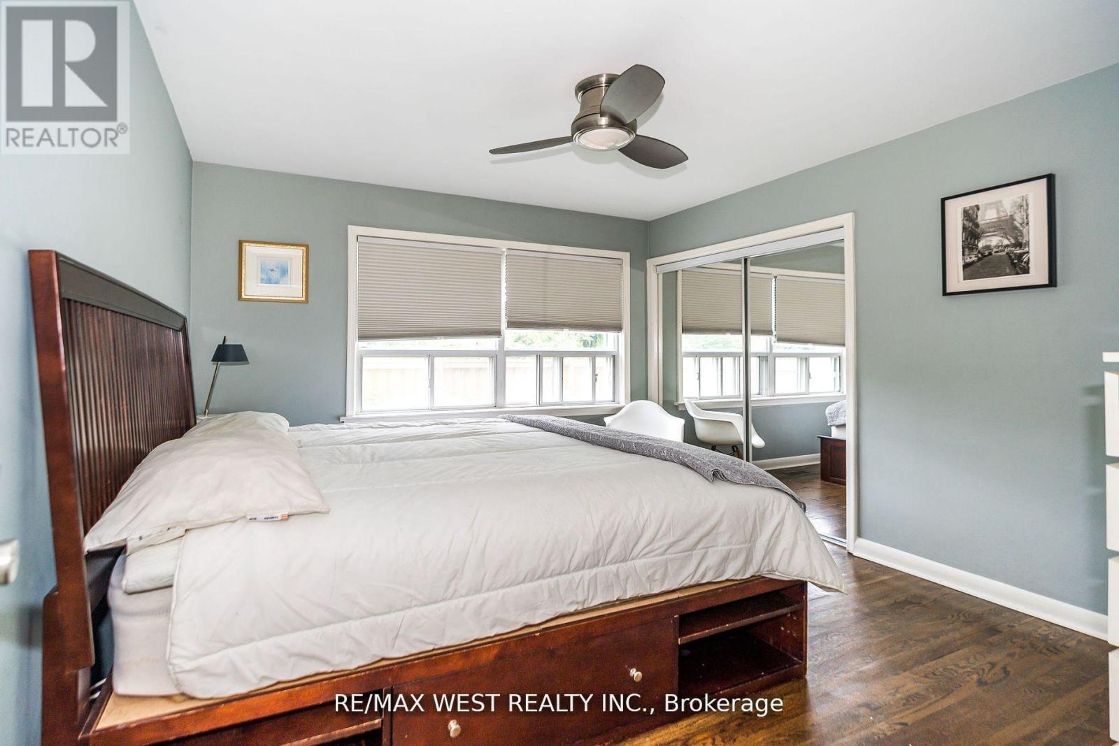 A bedroom with a bed, a ceiling fan, and a window with blinds.