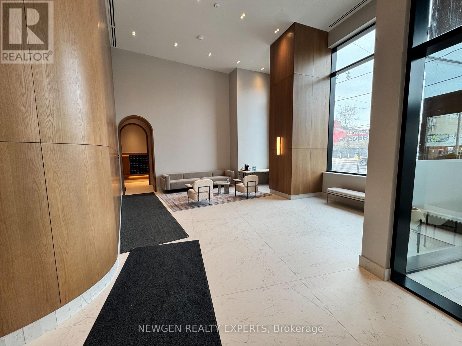 A lobby with a black carpet and a glass door.