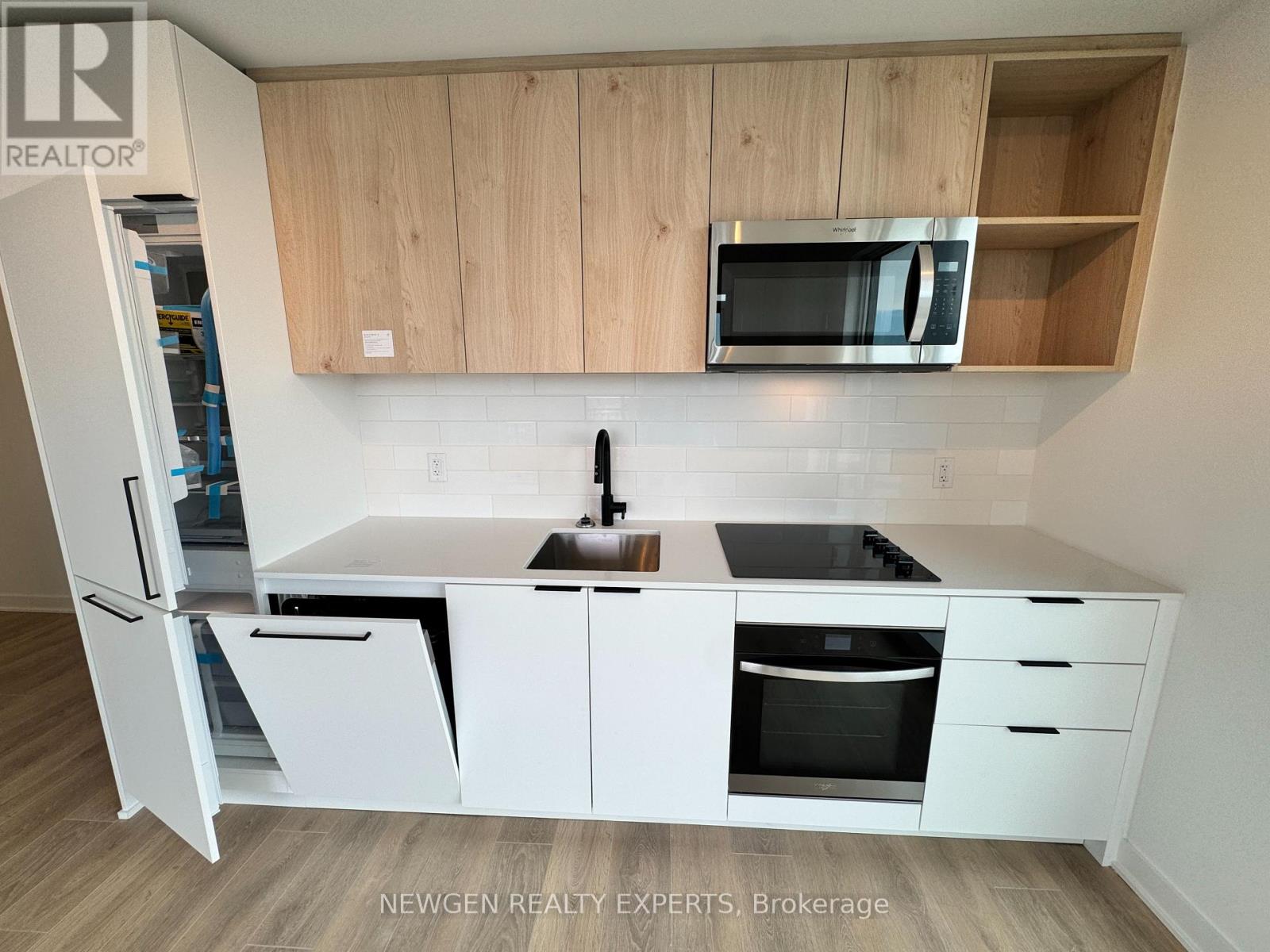 A kitchen with white cabinets and appliances, a sink, and a microwave.
