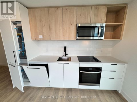 A kitchen with white cabinets and appliances, a sink, and a microwave.