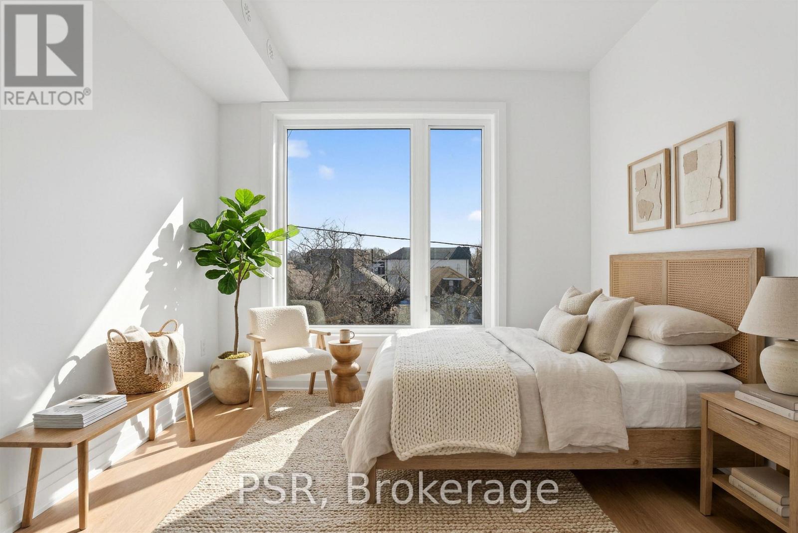 A bedroom with a large bed and a view of the outside through a large window.