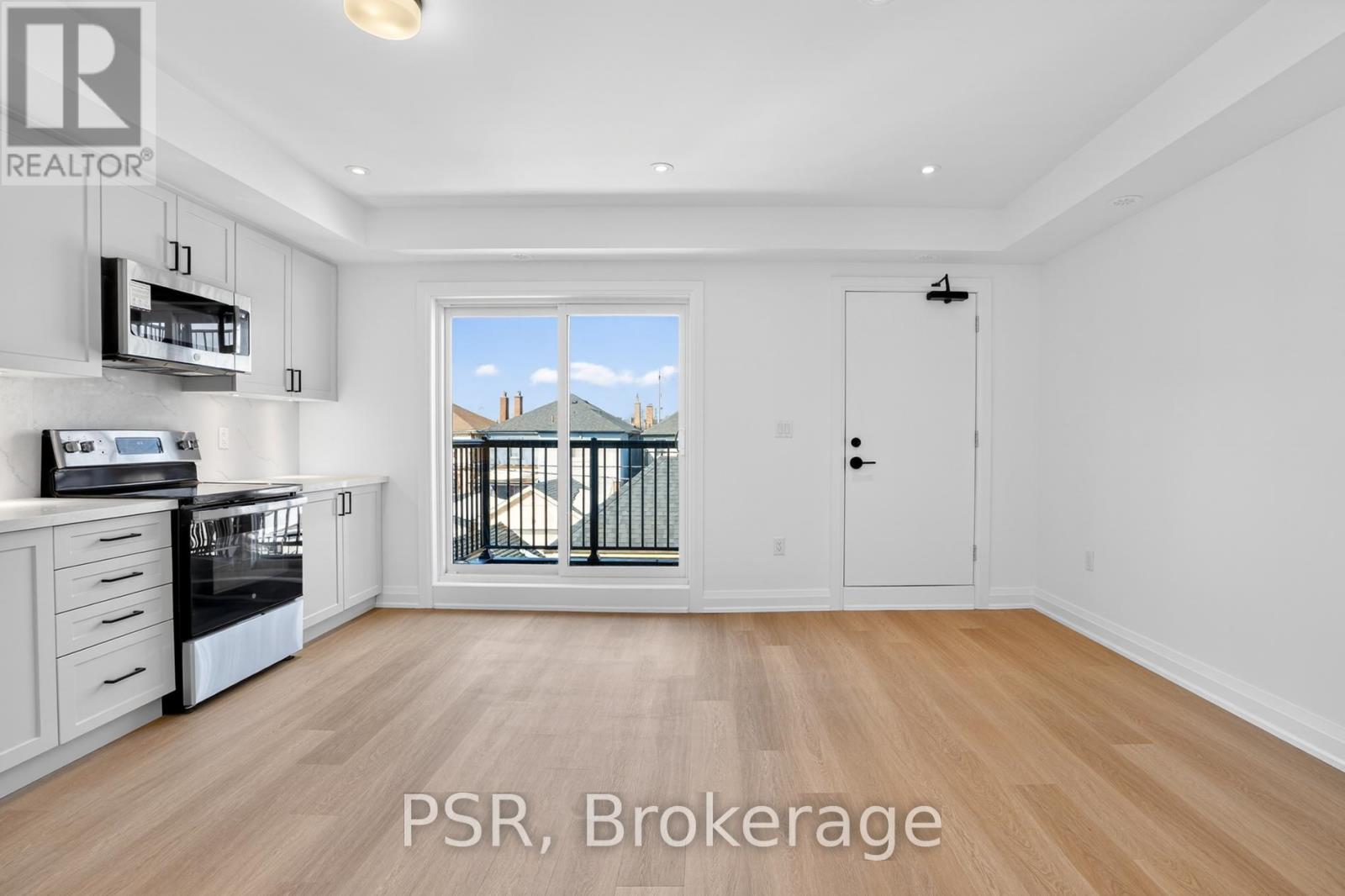 A spacious room with wooden flooring and a sliding glass door leading to a balcony.