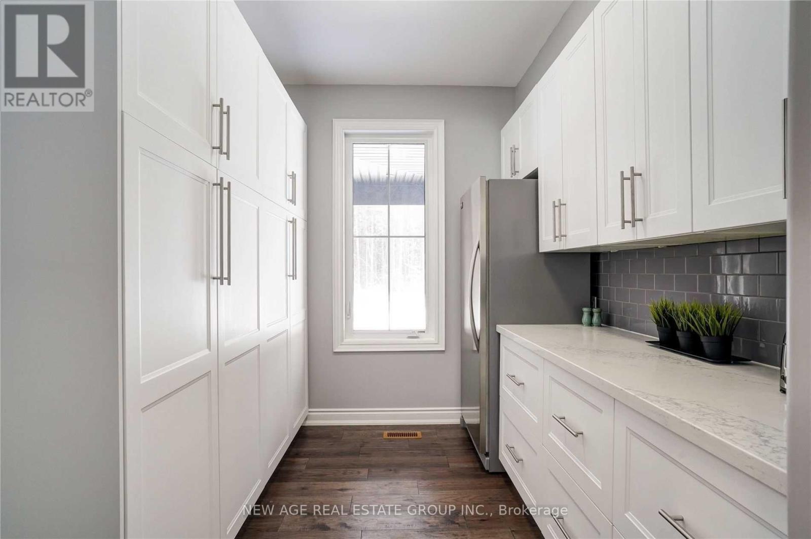 A kitchen with white cabinets and a marble countertop.