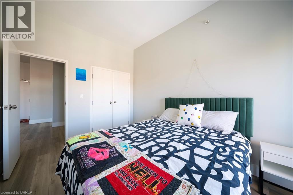 A bedroom with a bed covered in a quilt and a green headboard.