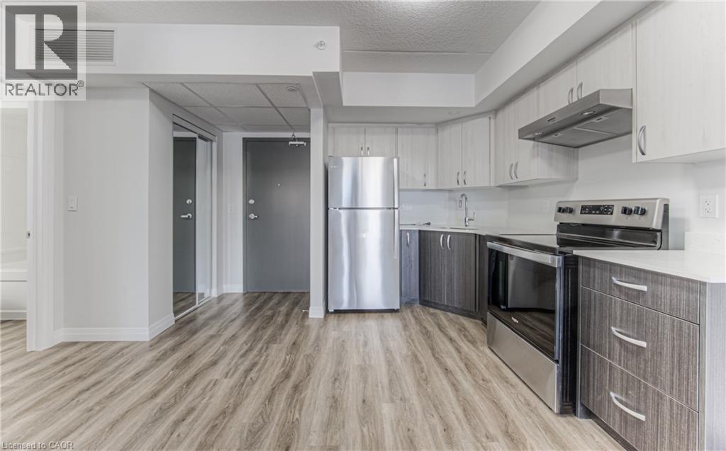 A modern kitchen with a stainless steel refrigerator and wooden flooring.