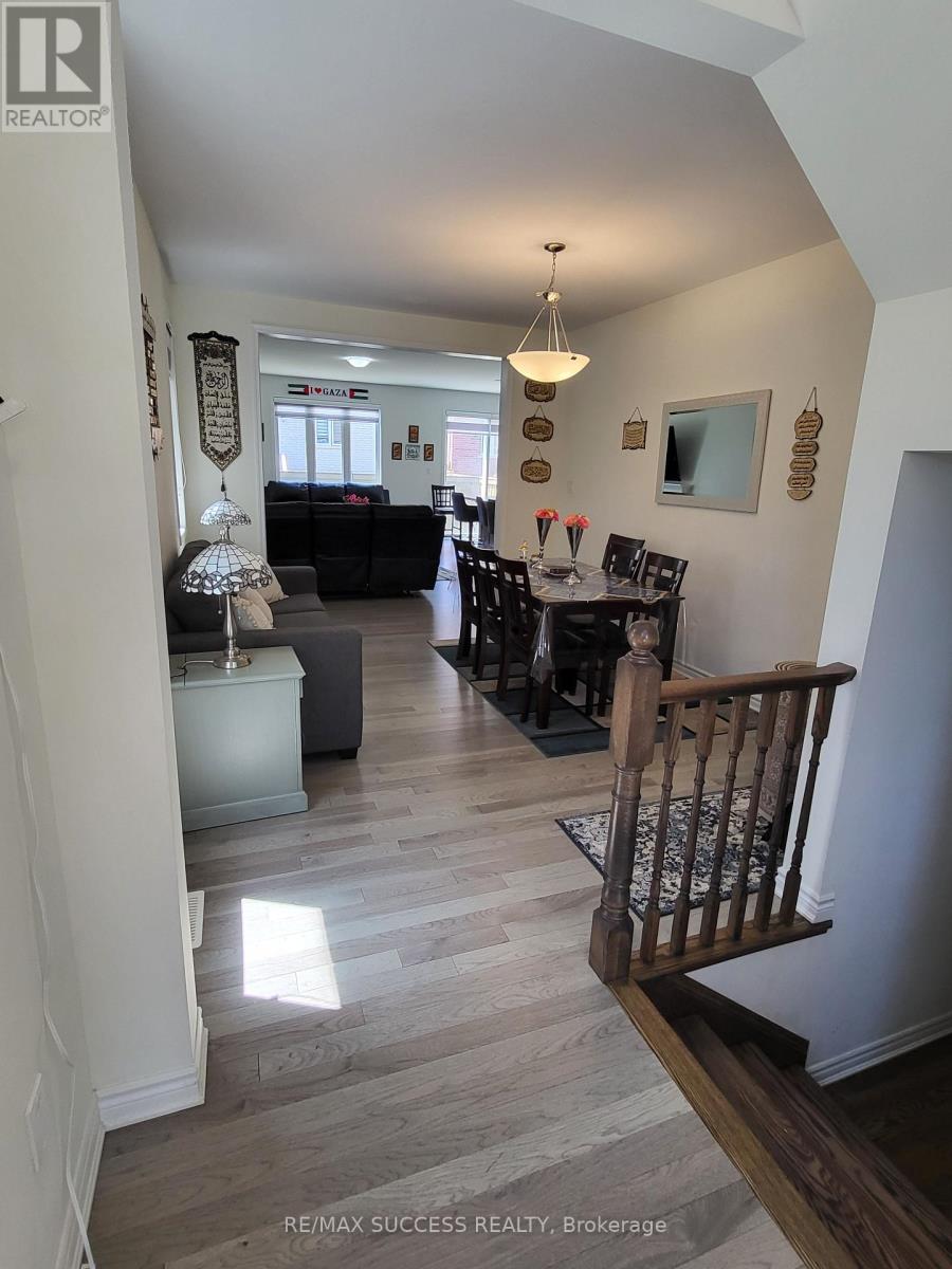 A hallway with a dining area and a kitchen in the background.