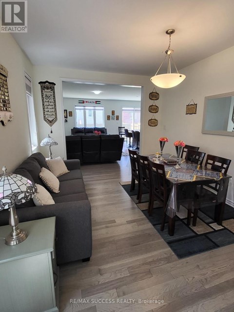 A well-lit living room with a grey sofa and a dining table set for six.