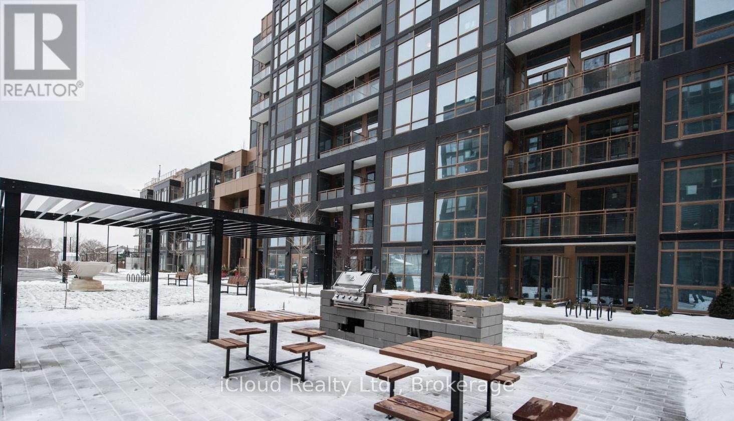 A snowy outdoor seating area in front of a modern building.