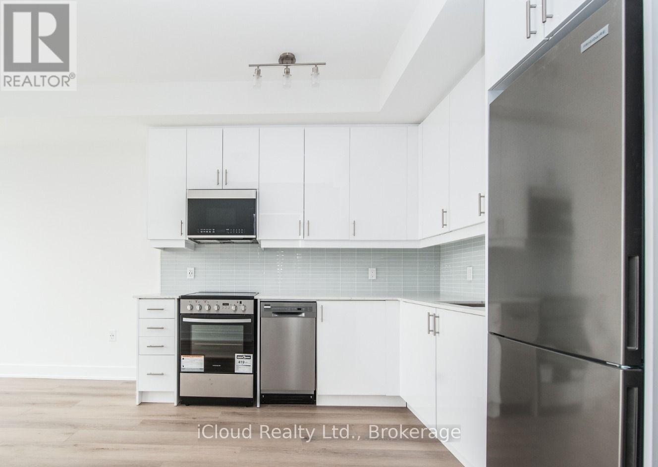 A modern kitchen with white cabinets and stainless steel appliances.