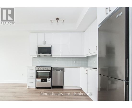 A modern kitchen with white cabinets and stainless steel appliances.