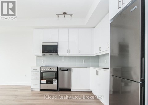 A modern kitchen with white cabinets and stainless steel appliances.