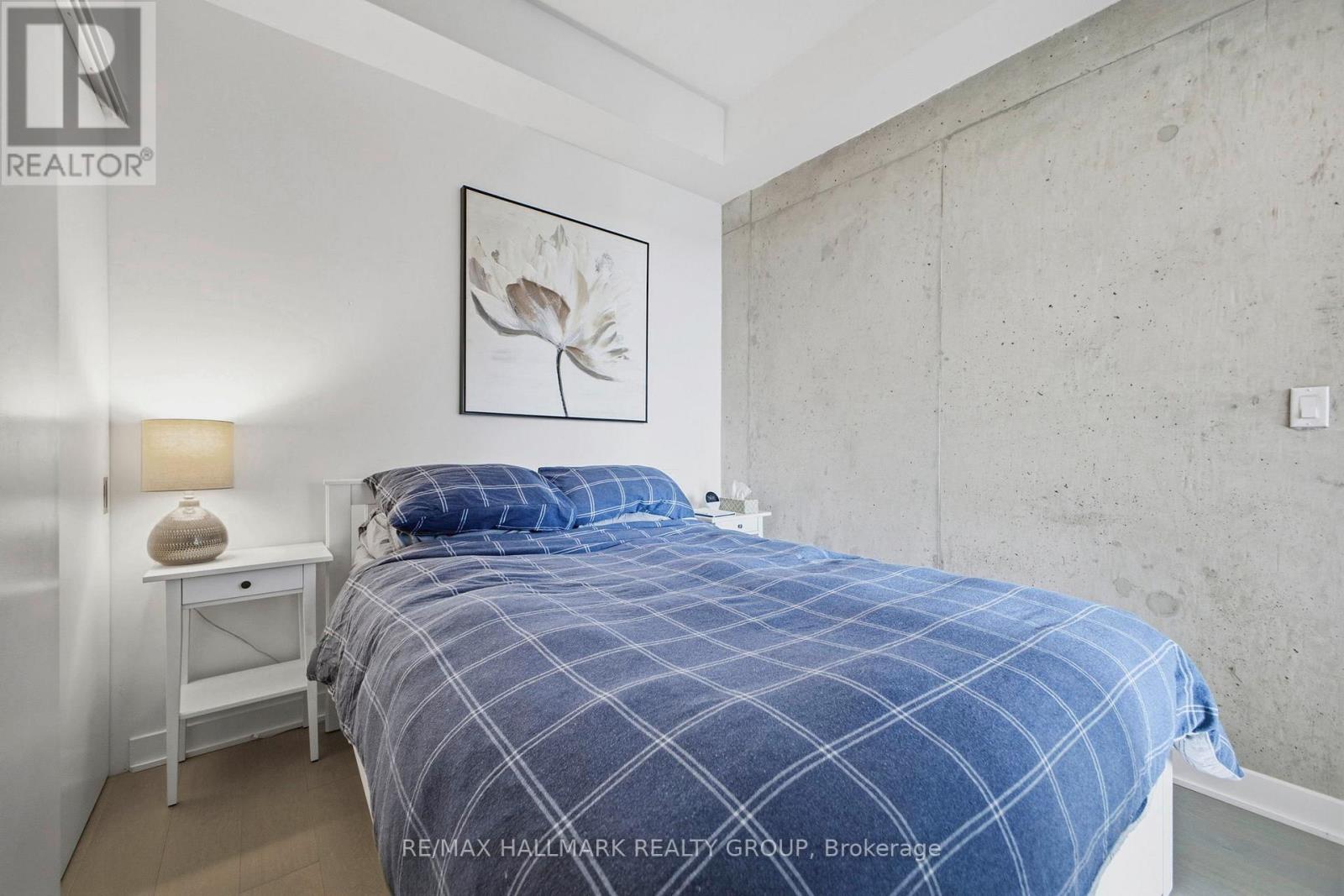 A bedroom with a bed, nightstand, and lamp.