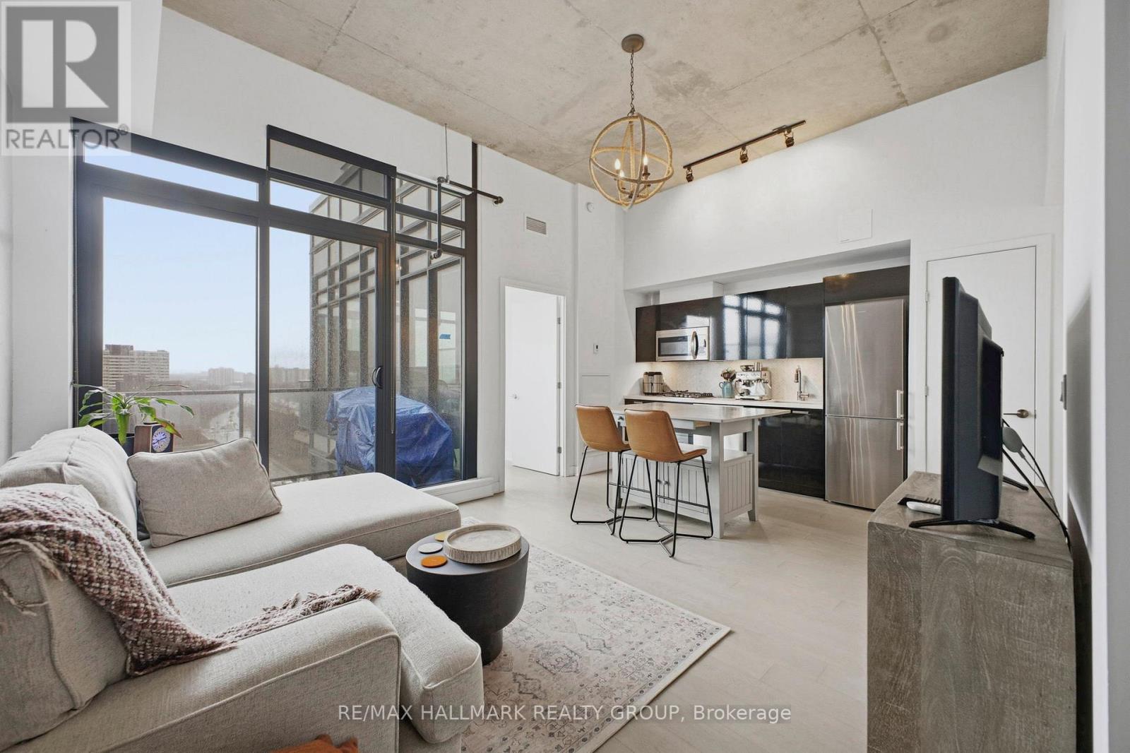 A modern living room with a grey sofa and a glass door leading to a balcony.