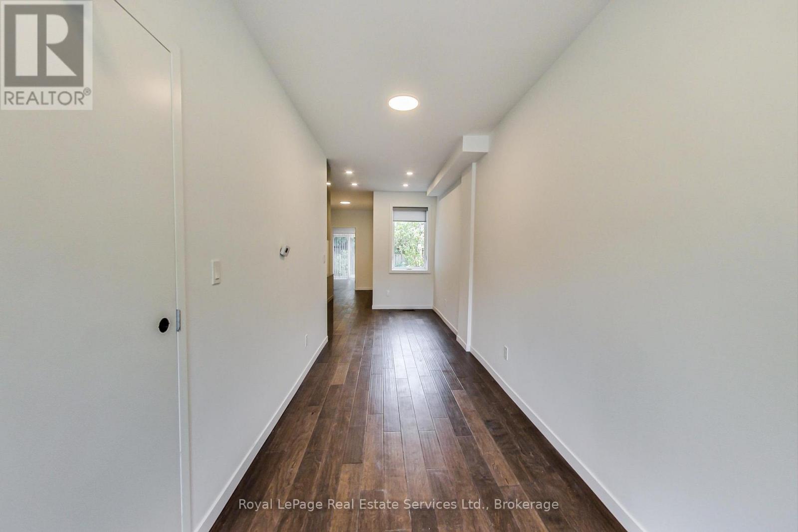 A long hallway with wooden floors and white walls.