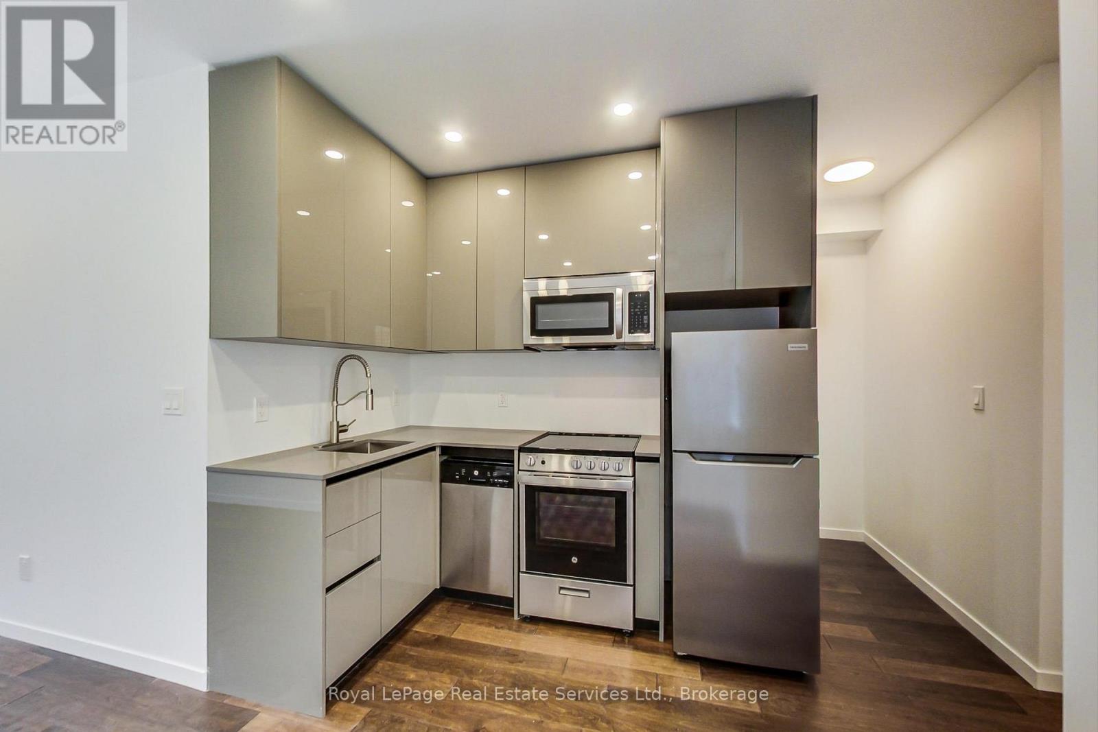 A modern kitchen with stainless steel appliances and wooden flooring.
