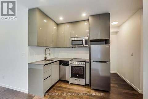 A modern kitchen with stainless steel appliances and wooden flooring.