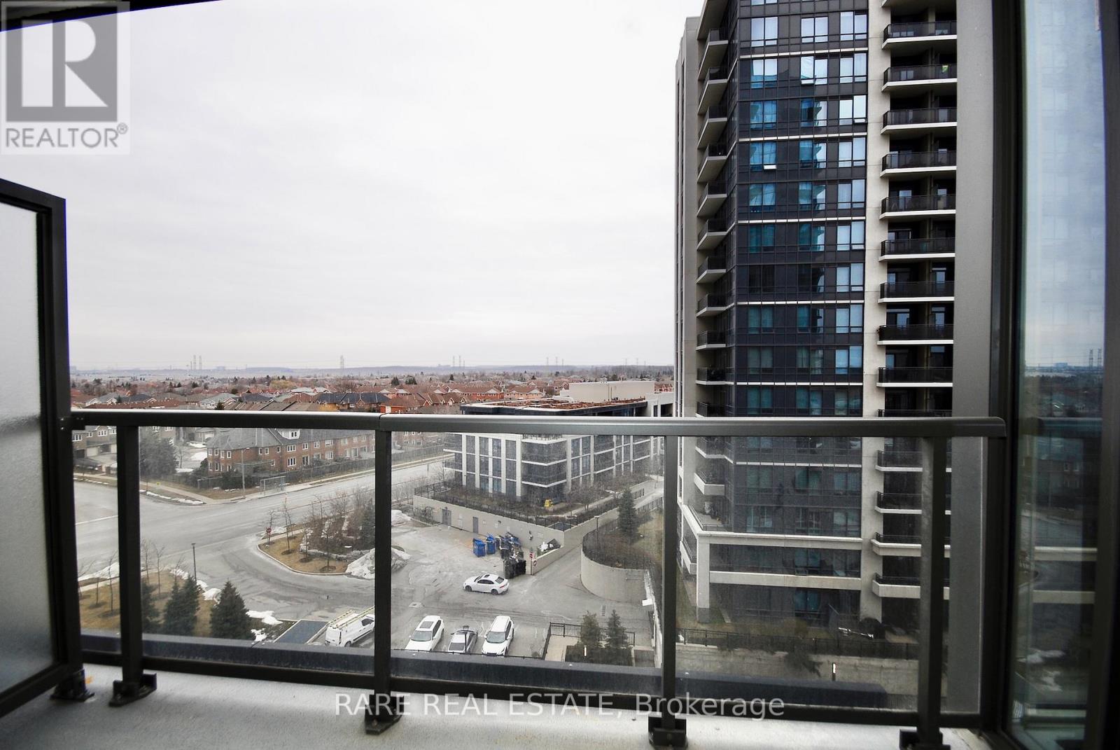 A view from a balcony of a cityscape with a tall building in the background.