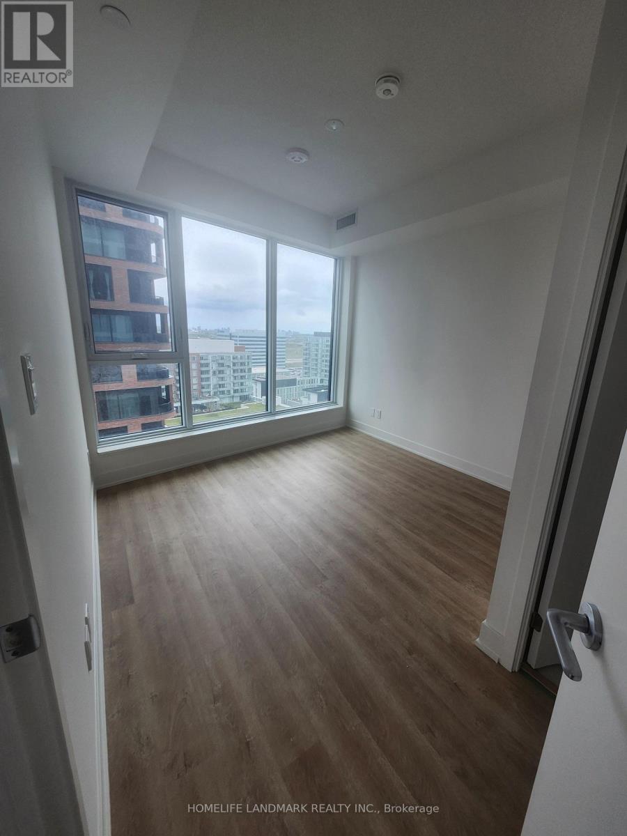 A room with wooden flooring and a view of the city through a large window.