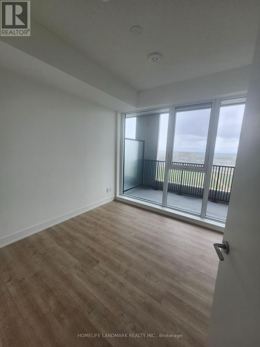 A room with wooden flooring and a sliding glass door leading to a balcony.