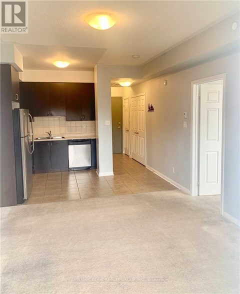 A kitchen with black cabinets and a white fridge is shown.
