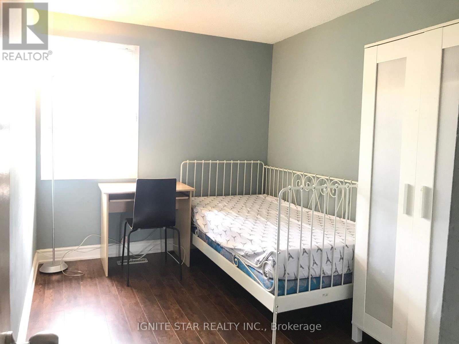 A bedroom with a bed, desk, and chair.