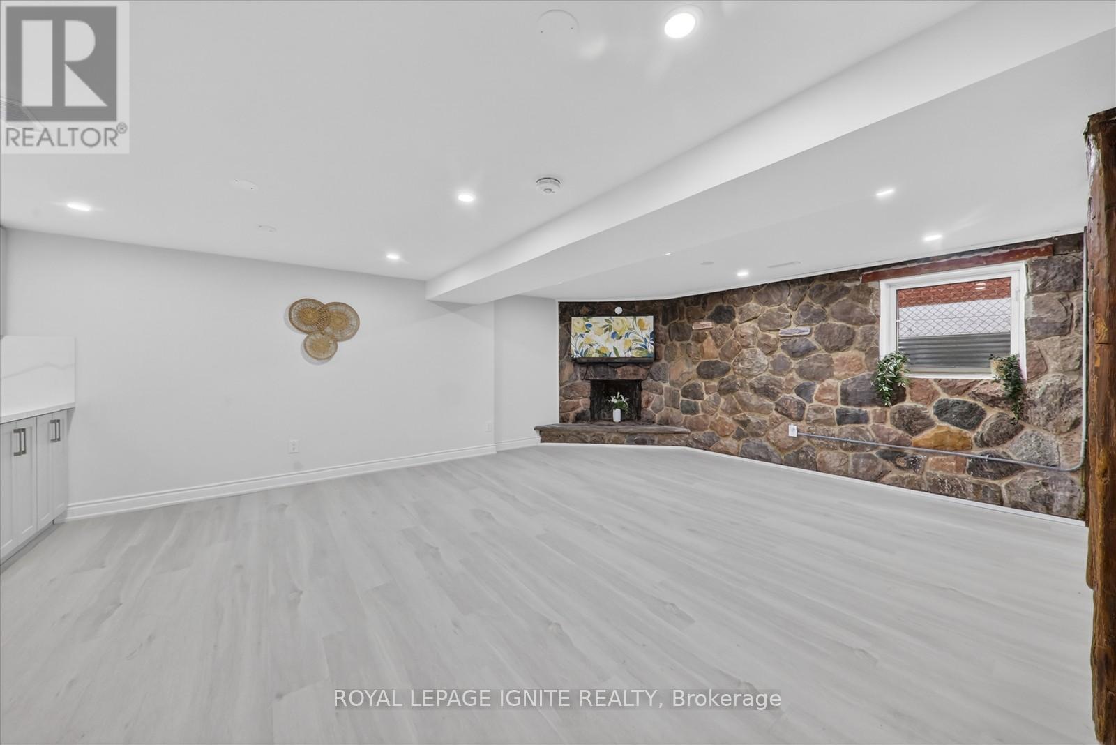 A spacious room with a stone wall and a flat screen TV mounted on it.