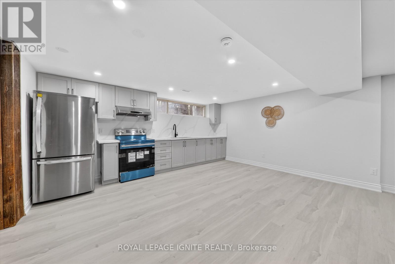A spacious kitchen with white walls and wooden flooring.