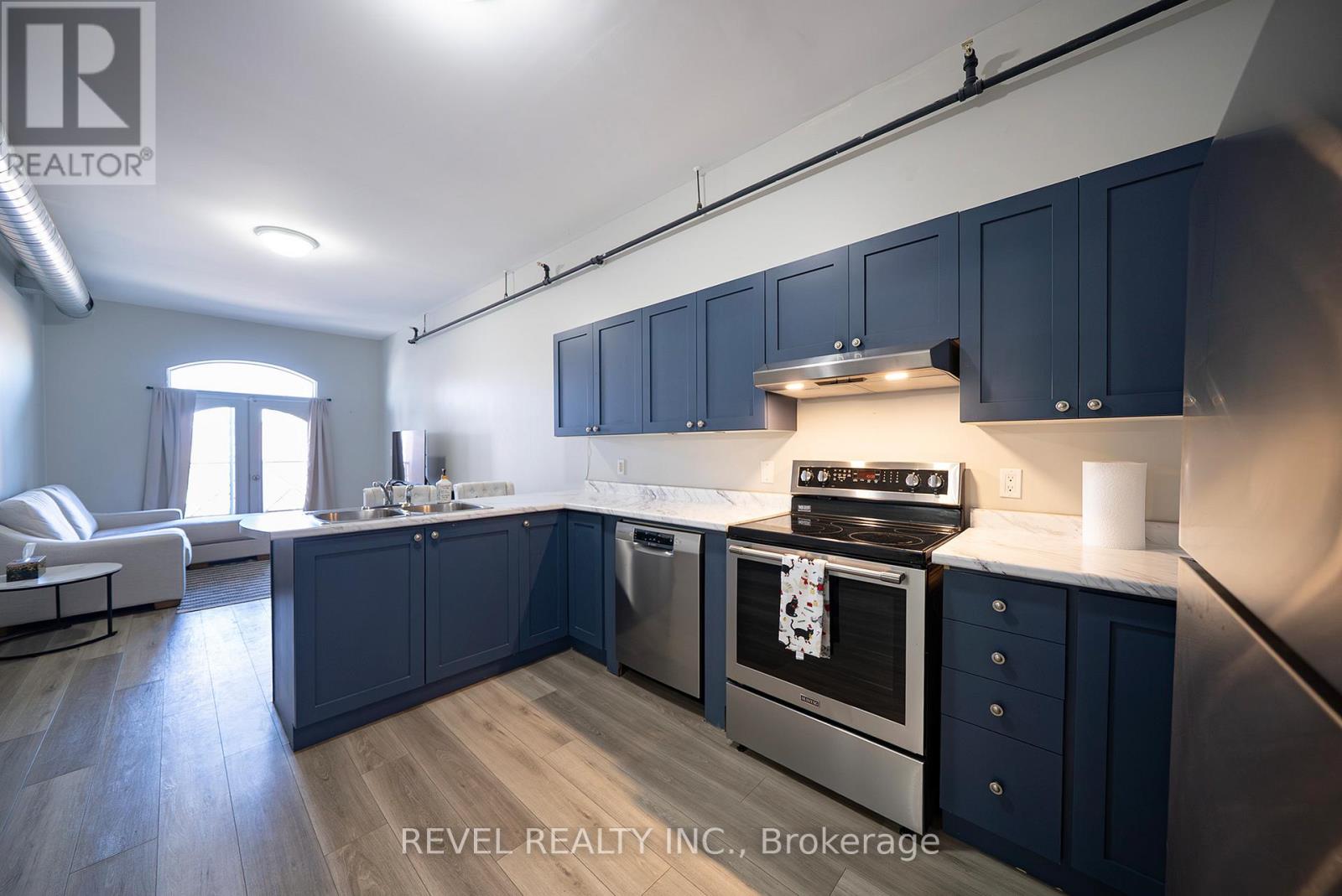A modern kitchen with dark blue cabinets and stainless steel appliances.