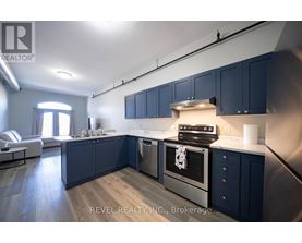A modern kitchen with dark blue cabinets and stainless steel appliances.