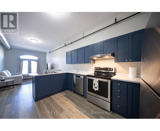 A modern kitchen with dark blue cabinets and stainless steel appliances.