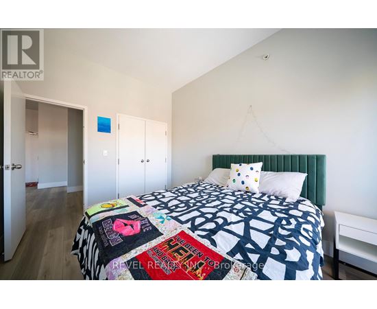 A bedroom with a bed covered in a quilt with many different words on it.