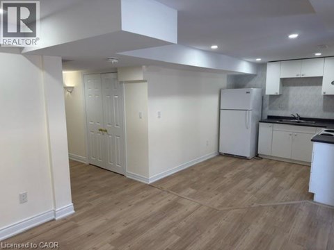 A kitchen area with white cabinets and a refrigerator.