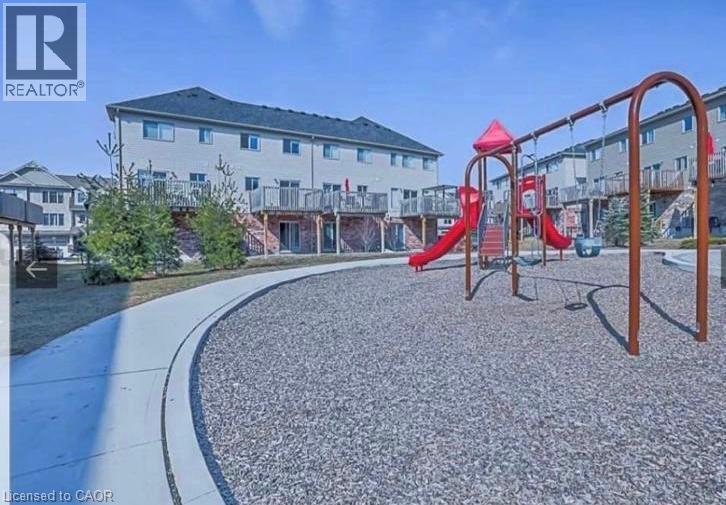 A playground with a red slide and a building in the background.