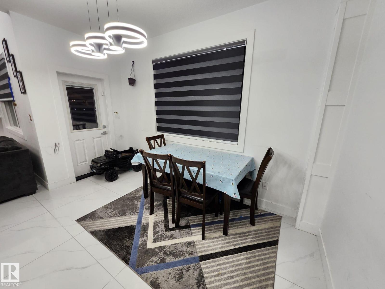 A dining room with a table set for two and a rug on the floor.