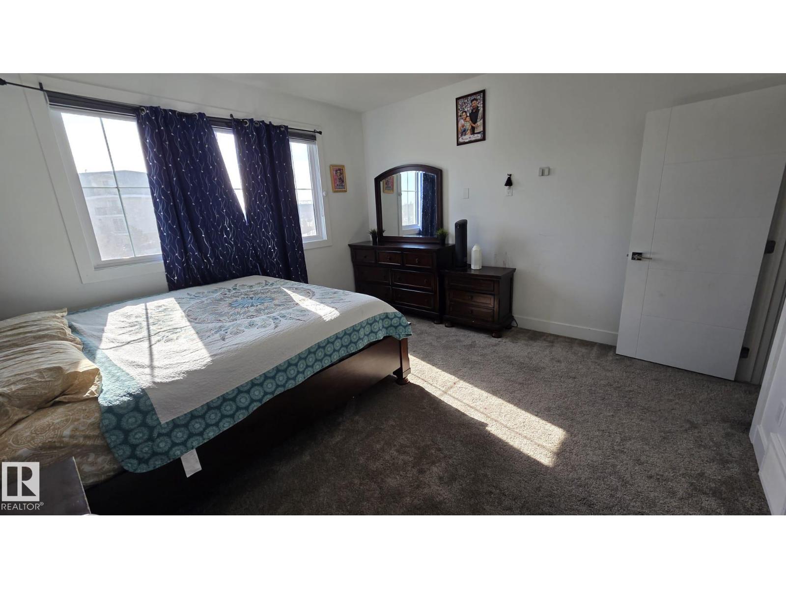 A bedroom with a bed, dresser, and mirror.