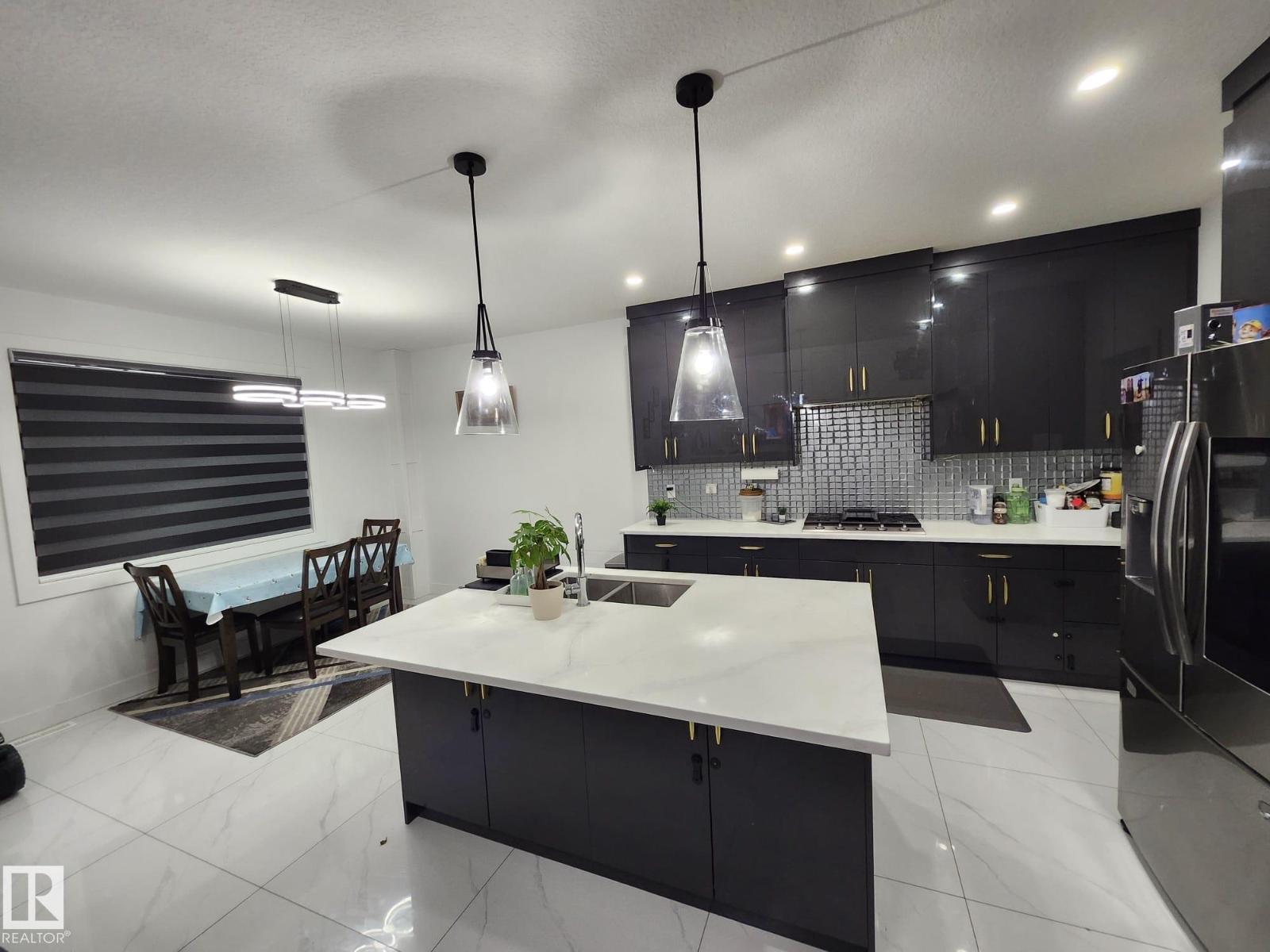 A modern kitchen with black cabinets and a white island.