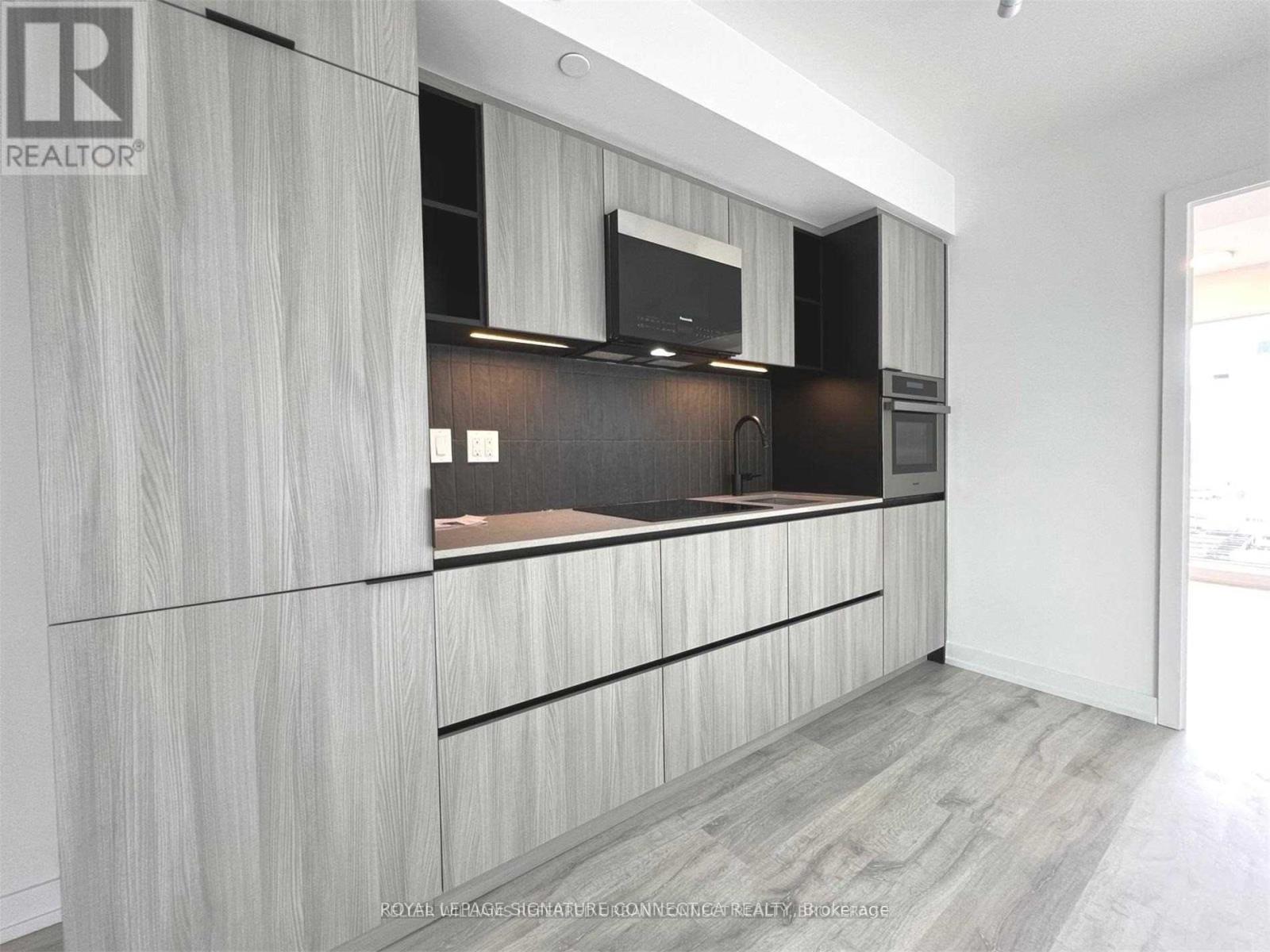 A modern kitchen with wooden cabinets and a black countertop.