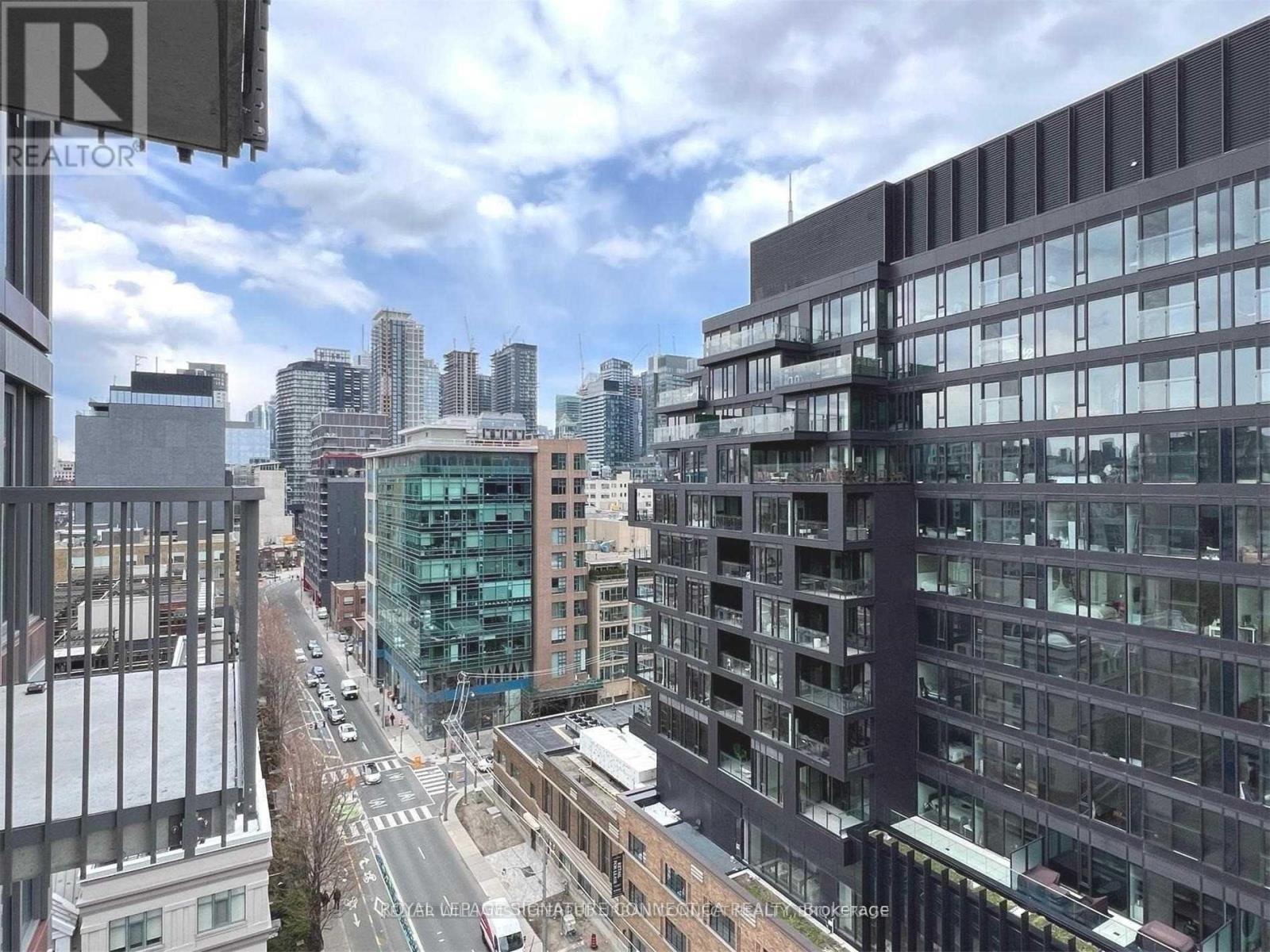 A city street with buildings on either side and a cloudy sky.