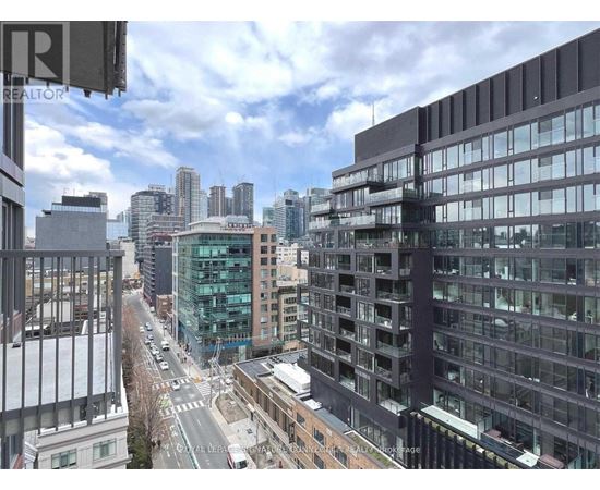 A city street with buildings on either side and a cloudy sky.