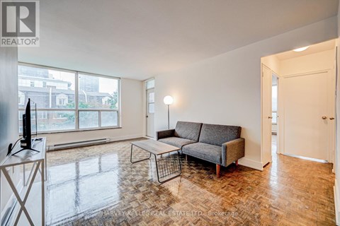 A living room with a grey sofa and a television on a stand.