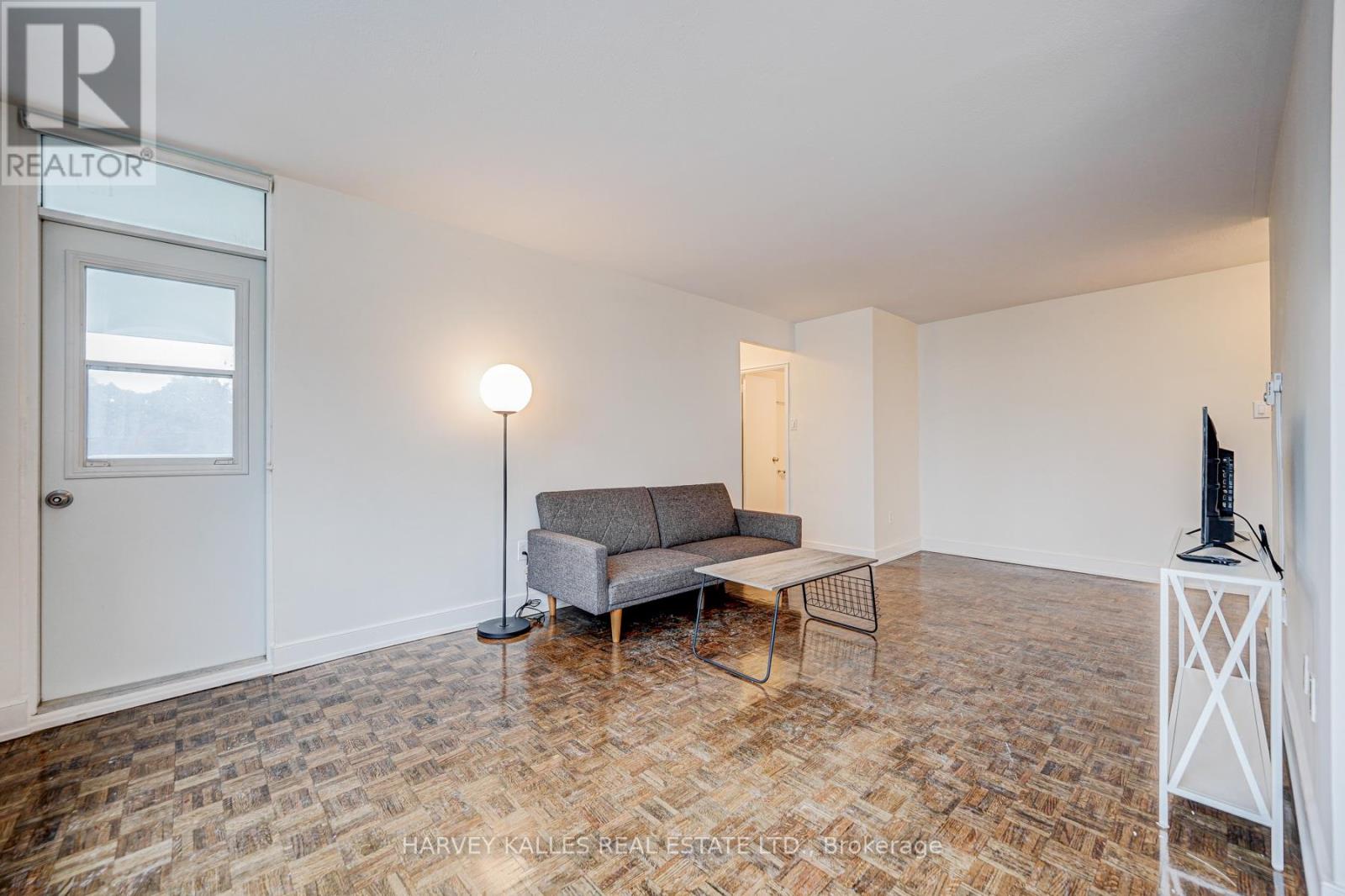 A living room with a grey sofa and a wooden floor.