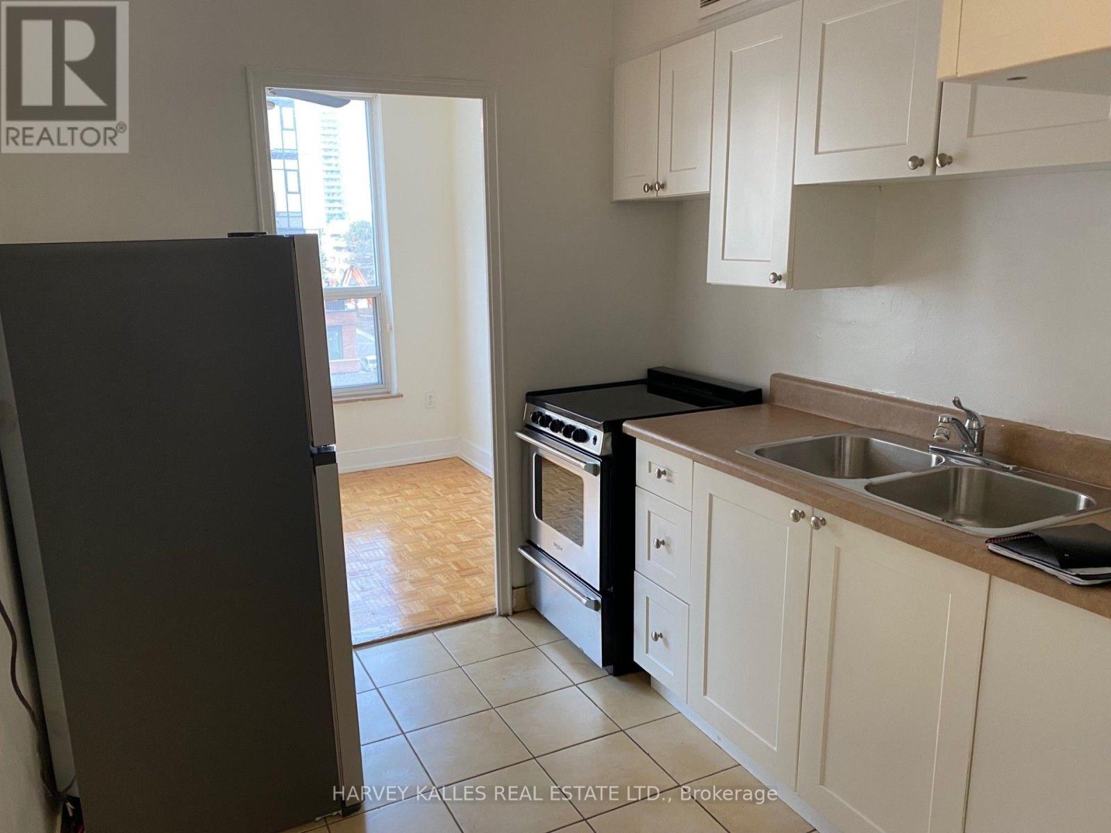 A kitchen with a refrigerator, sink, and oven.