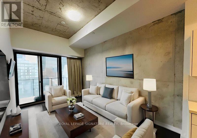 A living room with a white sofa and a painting on the wall.