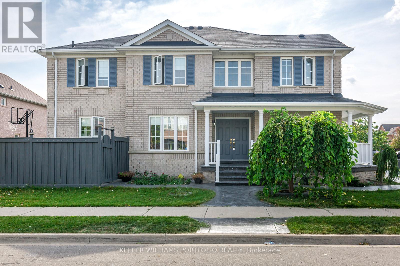 A house with a grey front yard and a white fence.