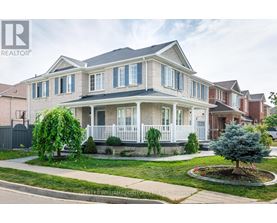 A large house with a white porch and a tree in the front yard.